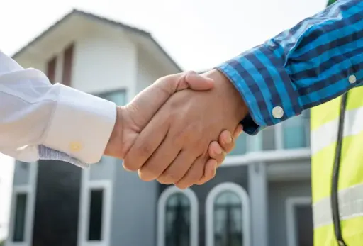 A property owner and a TX Sparks contractor shaking hands in front of a home
